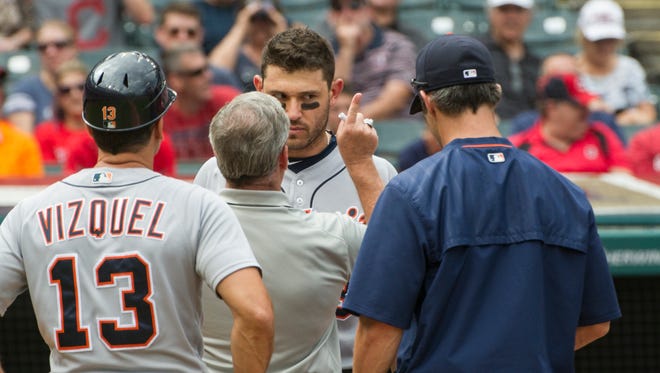 Detroit Tigers' Ian Kinsler is checked by a trainer after being hit in the head by Cleveland Indians pitcher Trevor Bauer during the third inning in Cleveland, Sunday, Sept. 18, 2016. Tigers coach Omar Vizquel (13) and manager Brad Ausmus look on.