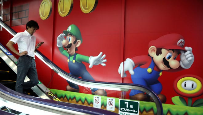 A shopper walks in front of Nintendo's Super Mario characters at an electronics store in Tokyo.