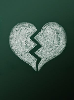 Broken heart on green blackboard.