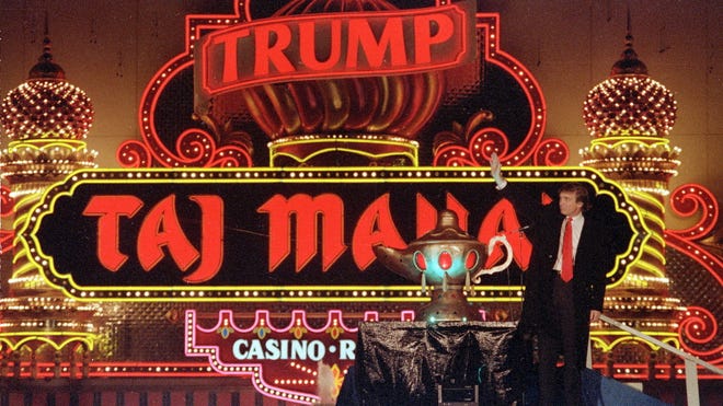 In this April 5, 1990 file photo, Donald Trump stands next to a genie lamp as the lights of his Trump Taj Mahal Casino Resort light up the evening sky marking the grand opening of the venture in Atlantic City, N.J.