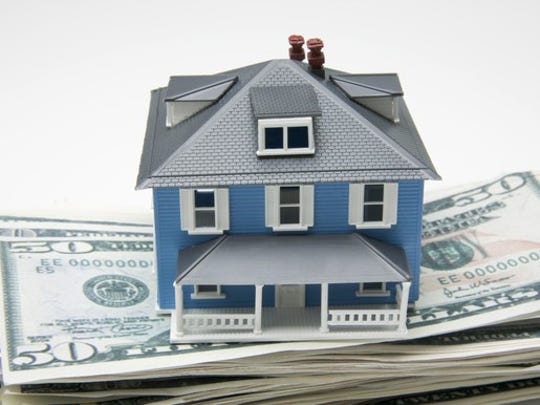 a small model house sitting on a stack of fifty dollar bills
