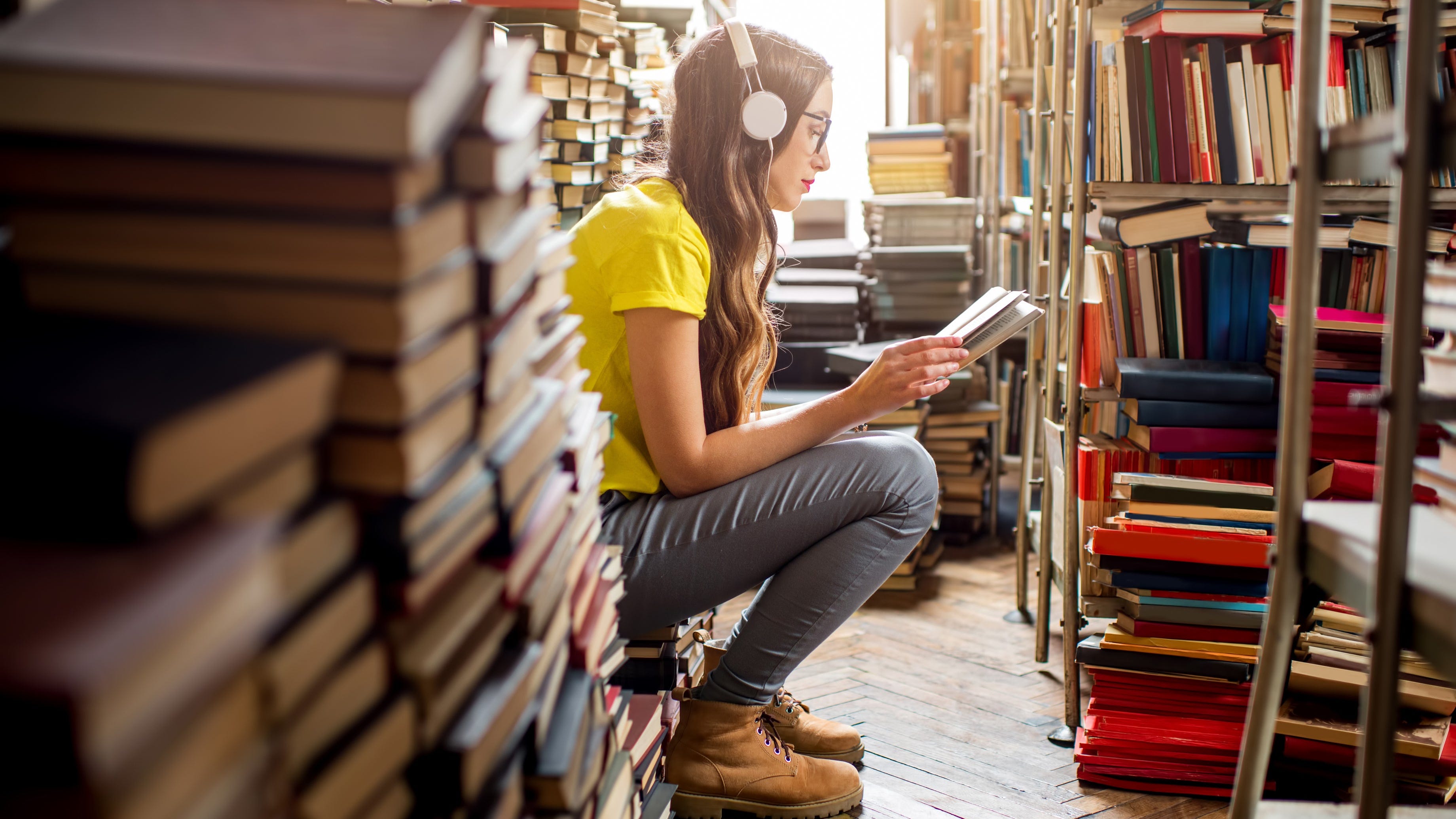 A young woman listens to music in a library.