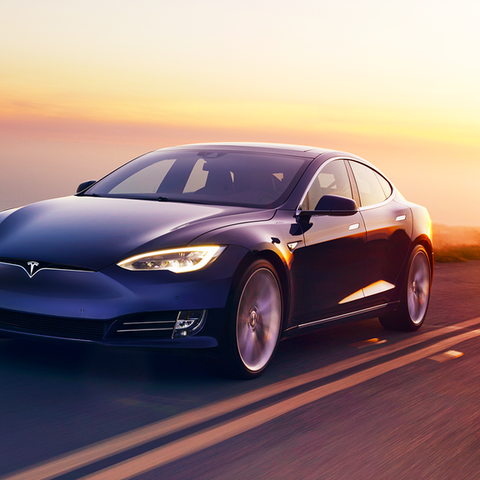 Blue Tesla Model S sedan on a road with the sun se