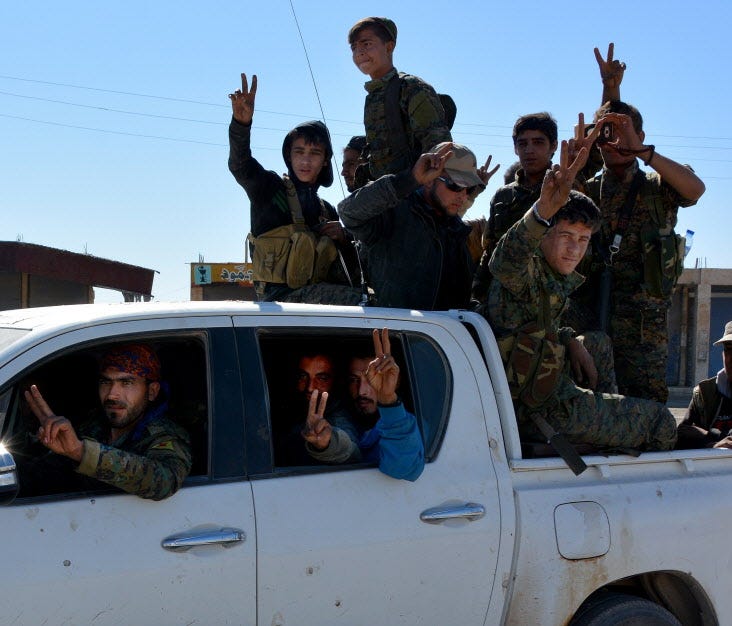 Syrian Democratic Forces flash victory signs in Raqqa, Syria, on Oct. 18 2017.