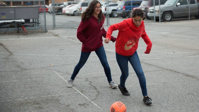 Jackie Moreno, 13, and classmate Andrea Casillas,12, play soccer on the basketball courts at La Academia Dolores Huerta, Tuesday December 6, 2016. The students call the blacktop la carnicería, or the meat market, because of the skinned knees and elbows it is known to inflict. A group of NMSU students recently raised money to get the school new athletic equipment.