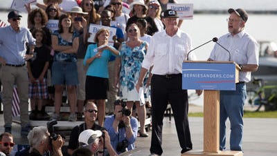 Ben Cohen, at podium left, and Jerry Greenfield, right, founders of Ben & Jerry's Homemade Inc., introduce Sen. Bernie Sanders at his presidential campaign kickoff on May 26 in Burlington, Vermont.