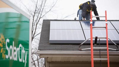 A SolarCity employee installs a solar panel.