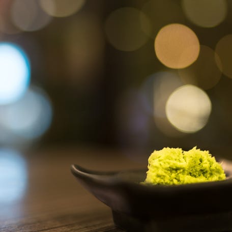 Wasabi in black saucer on wooden table with depth of field effect, Japanese food's condiment, bokeh background