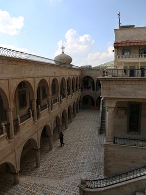 In this Thursday, April 2, 2015 photo, a man walks on the grounds of the Mar Matti monastery in the Christian town of Bashiqa, northern Iraq. As Islamic State group militants advanced toward this monastery in northern Iraq last year, the monks were determined to protect a fragile, vital piece of their heritage: They sent their library of centuries-old handwritten manuscripts to safety. Now the documents are hidden in an apartment in Iraq's Kurdish areas. (AP Photo/Bram Janssen) 