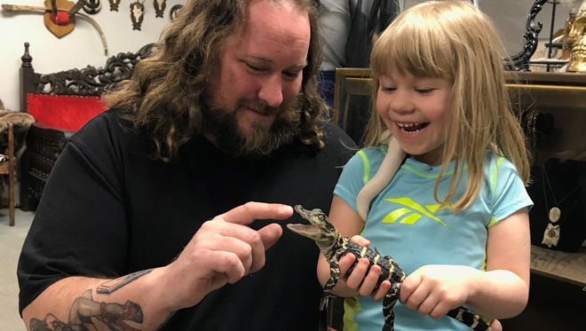 Jason Haack and his daughter Abby play with Yoshi, their 1-year-old American alligator. Haack would like to see city ordinance on exotic animals expanded to include a wider range of pets.