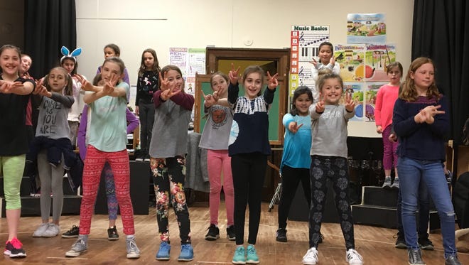 Fourth-grade students rehearse, front row from left: Claire Sewald, Valentina Ciuccio (second row in gray), Megan Logan, Tegan Hegarty, Sophie Lane (second row in pink pants), Lena Peachman, Kylie Eglowitz (second row in blue), Maren Restivo and Charlotte Thorburn. Back row from left: Madeline Smith, Amelia Regan, Emmy Christiansen, Chloe Zeng and Anna Mangold.