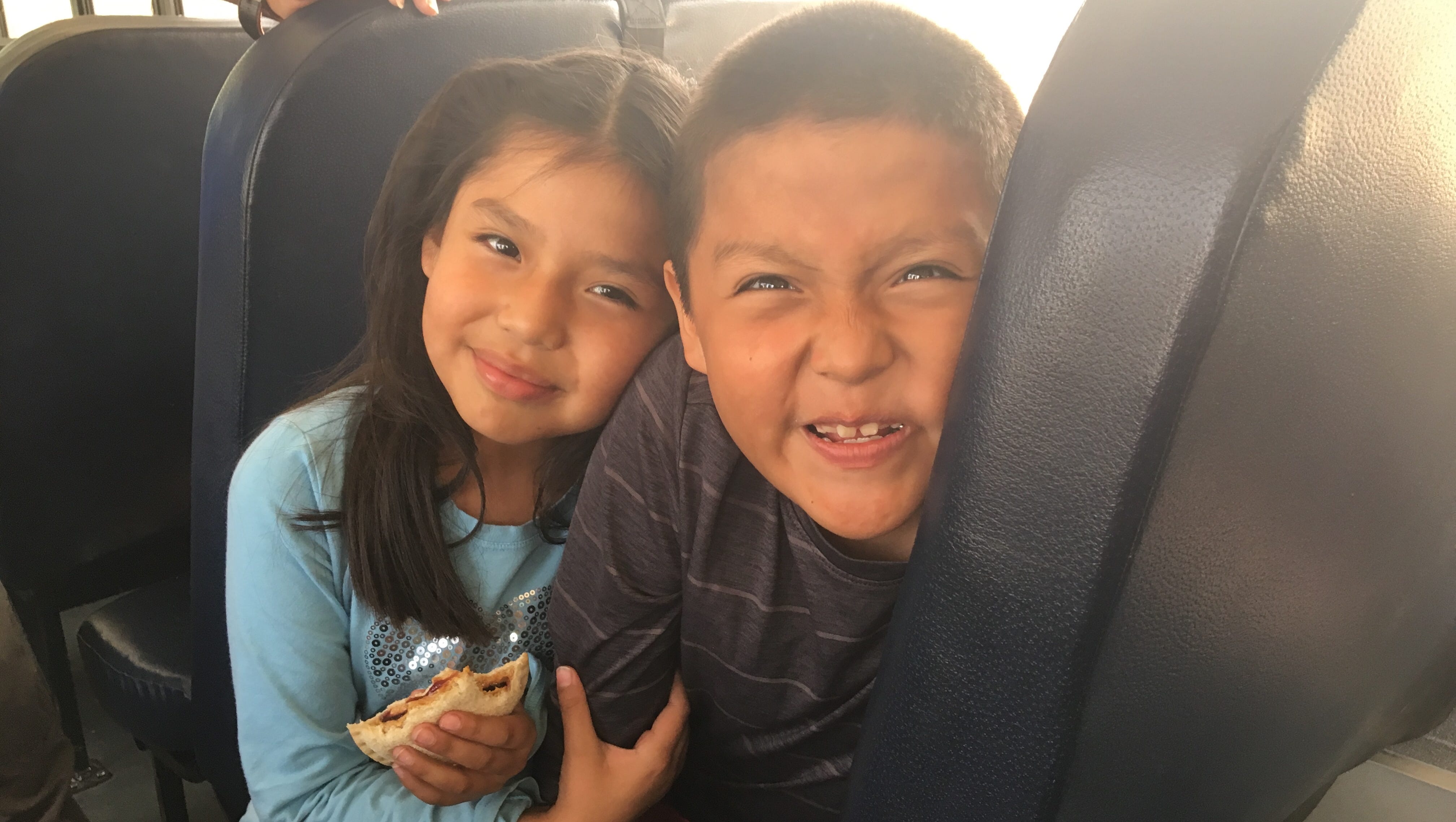 Ava Cook, 7, eats a peanut butter and jelly sandwich on a school bus with her silly 8-year-old brother, Anthony.