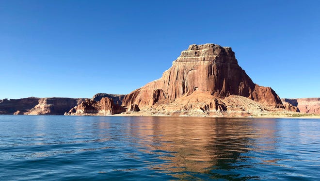A sandstone butte towers over the waters of Lake Powell near Page, Arizona.