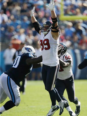 Texans defensive end J.J. Watt leaps to try blocking a pass in the second quarter as Titans guard Chance Warmack, left, blocks another Texans defender.