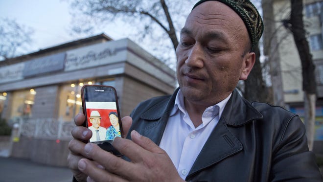 Omir Bekali shows a photo of his parents, whom he believes have been detained in China, in Almaty, Kazakhstan.