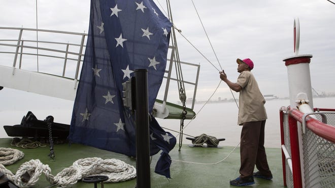 In this March 15, 2015 file photo, Dwayne McCornick, a deck hand on the Natchez steamboat for 16 years, raises the Union Jack naval flag on the Mississippi River in New Orleans.