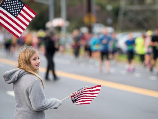 Onlookers greet marathon runners with waving American