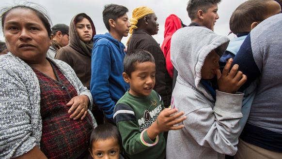 Central American migrants line up to get food at their