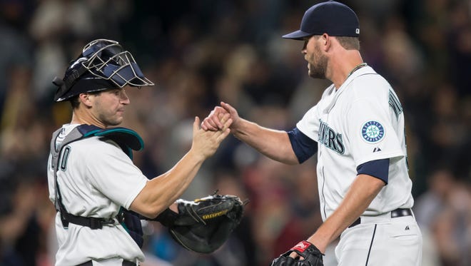 Seattle Mariners pitcher Tom Wilhelmsen, right, is congratulated by catcher Mike Zunino after Wilhelmsen earned a save in a baseball game against the Oakland Athletics, Tuesday, Aug. 25, 2015, in Seattle. The Mariners won 6-5.