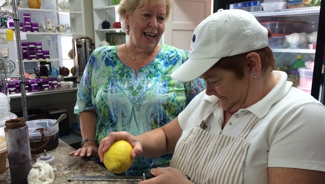 Wisteria Tea Room owner Bobbie Schwartz looks on as chef Susan Coffman grates lemon zest onto a dessert.