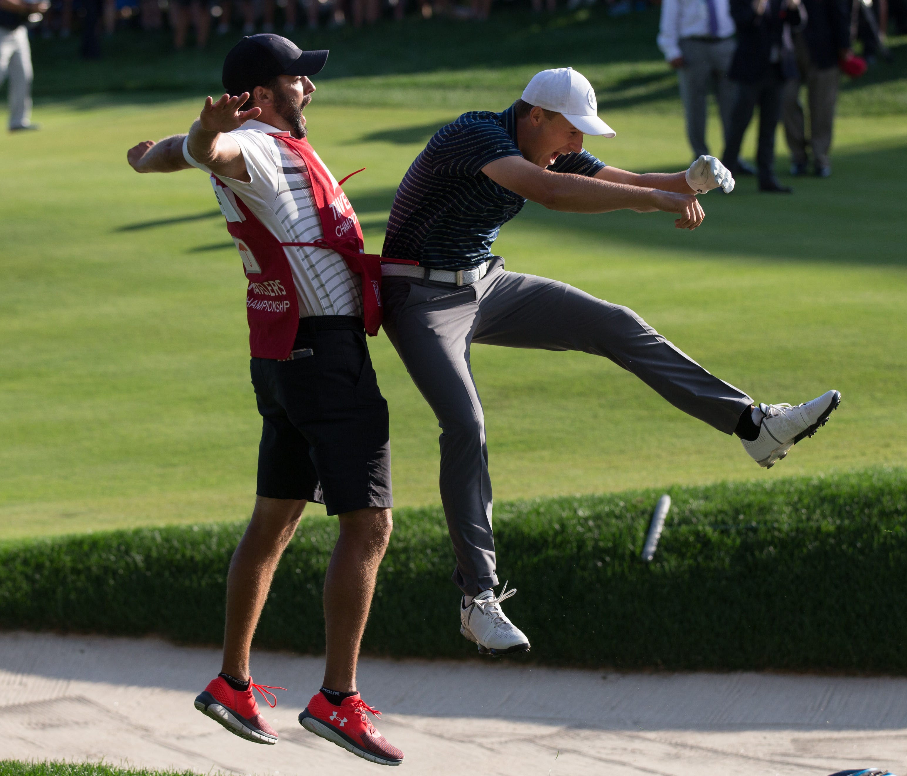 Jordan Spieth and his  caddie Michael Greller react after chipping out of the sand for a birdie during the first playoff hole of the final round of the Travelers Championship golf tournament at TPC River Highlands on June 25.