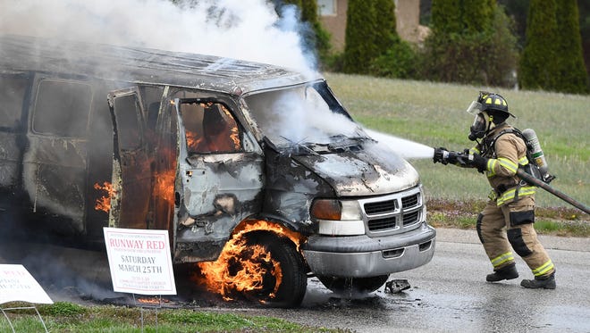 A Henderson City Fireman uses a water hose to extinguish a burning church van that was being used to shuttle passengers to a charity fundraiser at Community Baptist Church Saturday. No one was injured in the fire, but the 15-passenger van was destroyed and a nearby car was damaged, March 25, 2017.