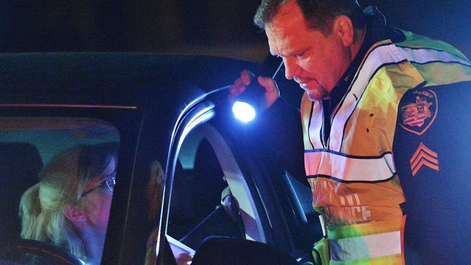 Sgt. Mike Walsh of the Summit County Sheriff's Office inspects a motorist's license at a sobriety checkpoint Dec.15 on East Turkeyfoot Road in Green.