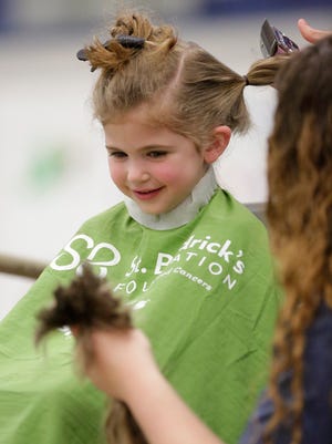 Roslyn Munson, 5, of Fond du Lac looks at a lock of hair that was just cut off her head at the St. Baldrick's Festival at the Fond du Lac County Fairgrounds Sunday, March 26, 2017. The event raises money for child cancer patients.