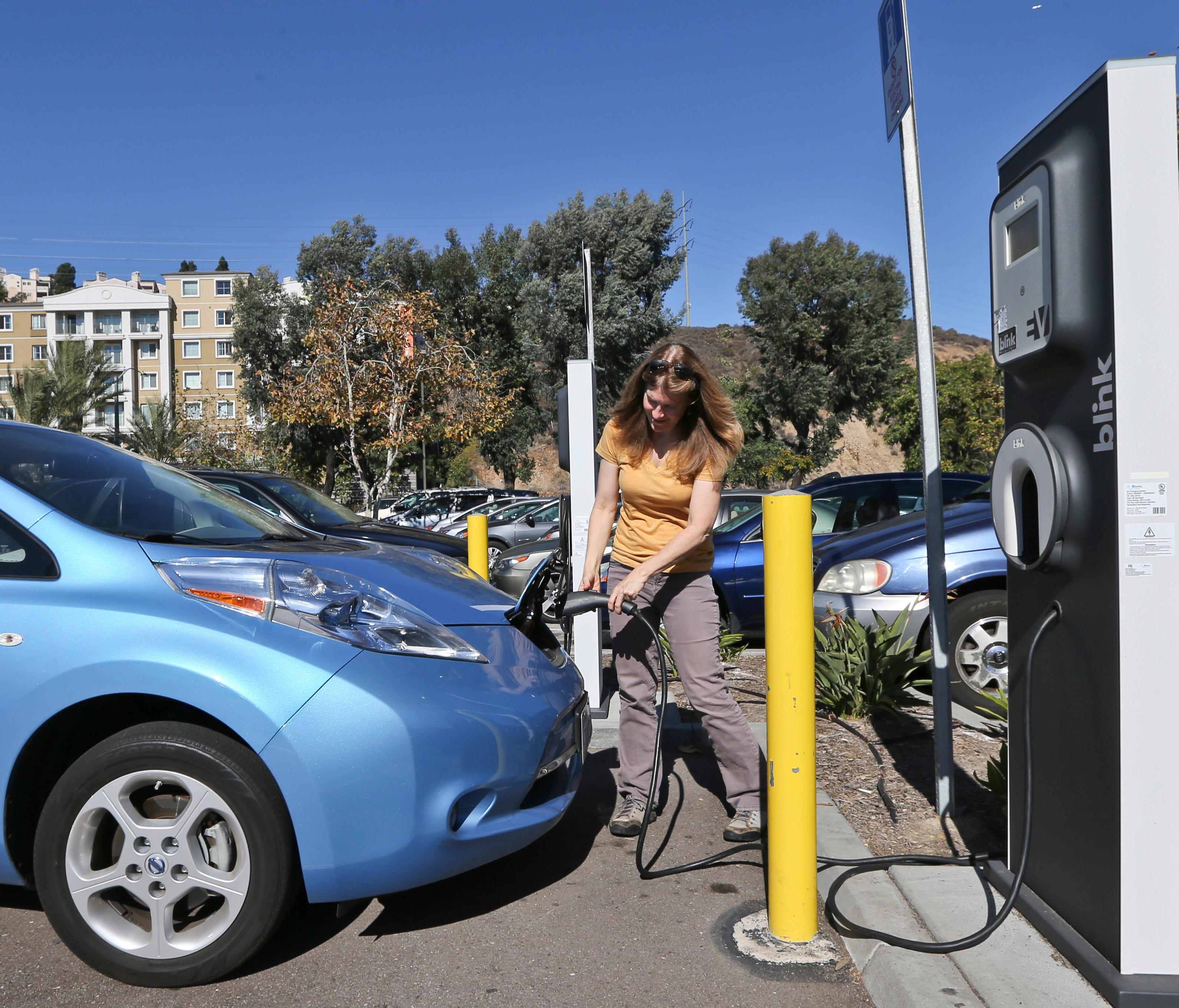 Angie Vorhies plugs in the charging cord to her Nissan Leaf electric vehicle  at a mall in San Diego in this 2013 file photo