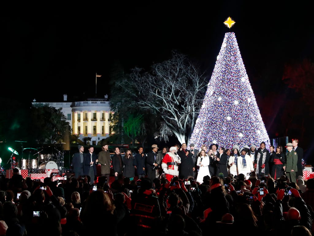 President Obama, with Michelle Obama and daughter Sasha, sing with Santa Claus and others during the lighting ceremony for the 2016 National Christmas Tree on the Ellipse near the White House in Washington, D.C.