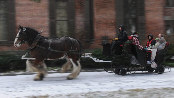Passengers on a sleigh pulled by Clydesdales pass by the home of Rutherford B. Hayes. The Hayes museum will be hosting sleigh rides in Spiegel Grove starting Tuesday, but the National Weather Service does not predict a snowy Christmas in the area.