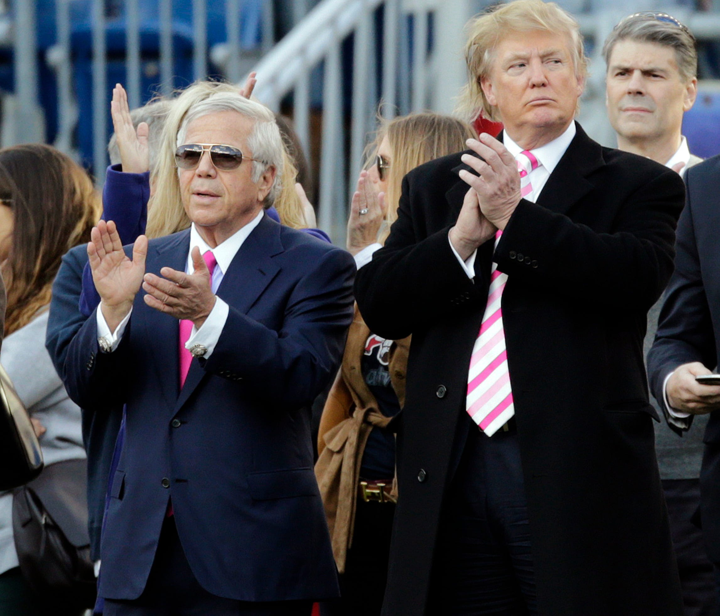 New England Patriots owner Robert Kraft, left, and President Donald Trump, right, applaud on the field before an NFL game back in 2012.