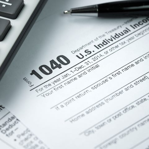 IRS 1040 form with pen and calculator sitting on...