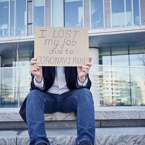 Man holding sign over his face stating he lost job