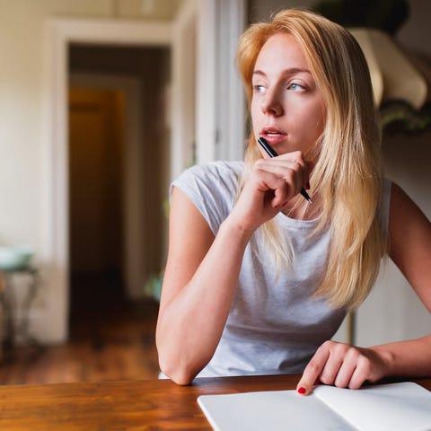 Woman with pen and notebook looking off into the d