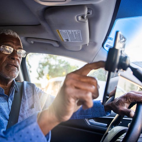 Senior gig worker using ride sharing app while in 