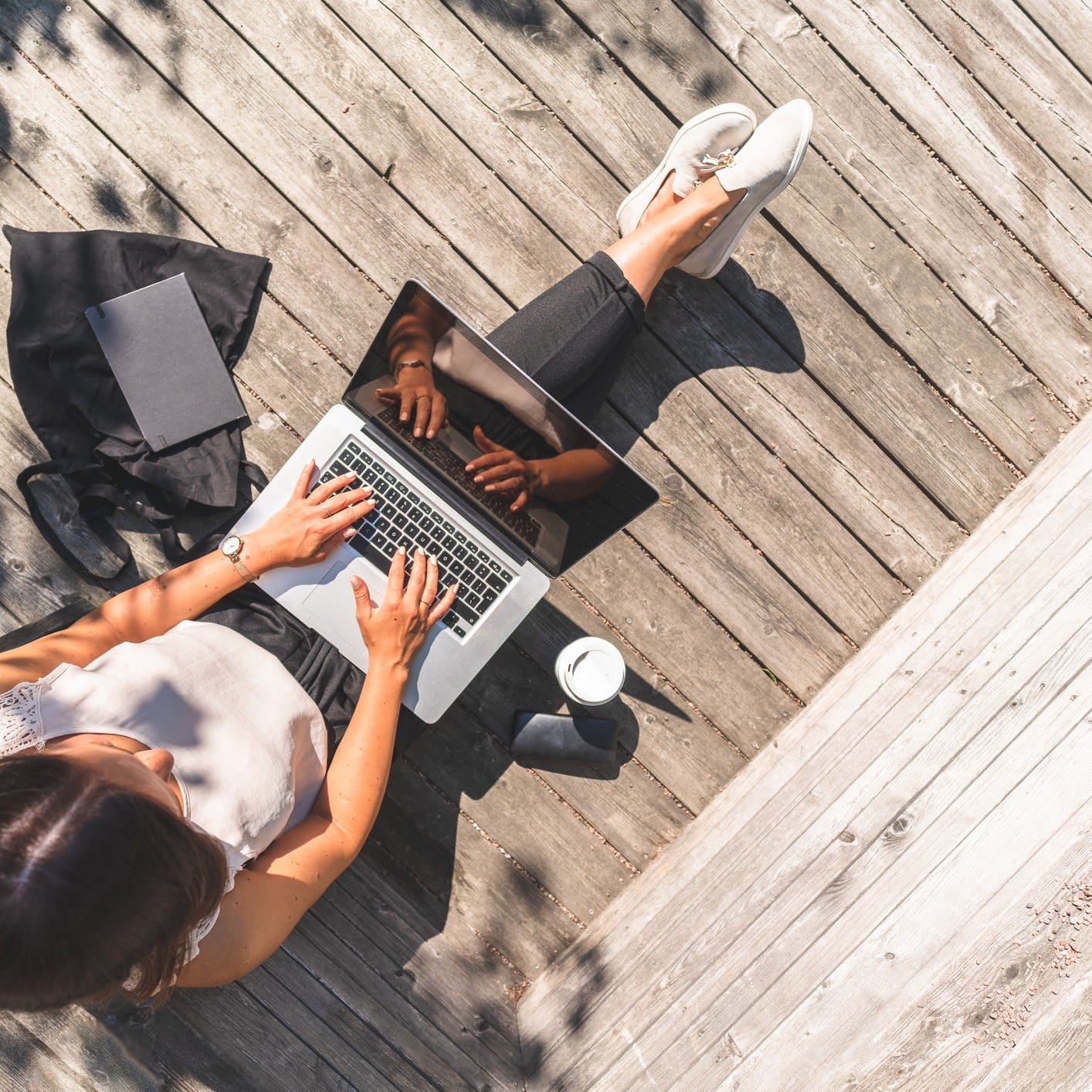 Female gig worker working on her laptop outside.