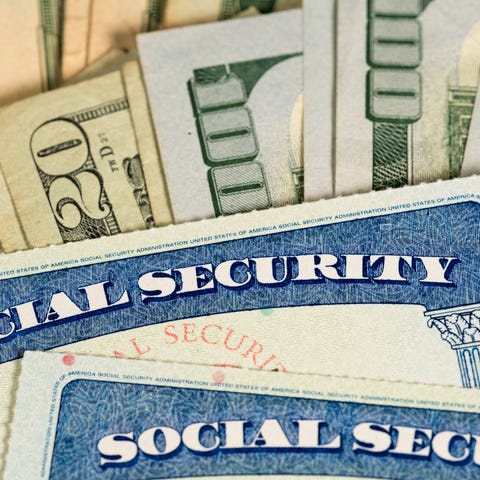 Pair of Social Security cards on a pile of bills