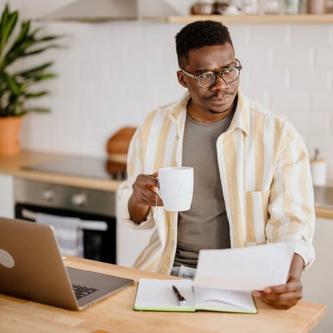 Man working from home reviewing a sheet of paper.