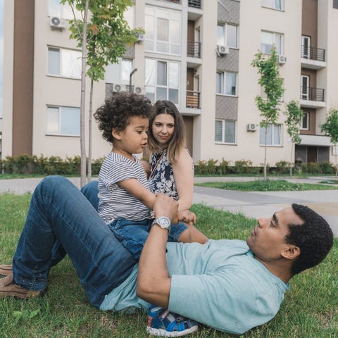 A family sits in the grass outside of their apartm