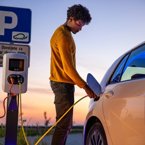 Person charging electric vehicle with nice sunset 