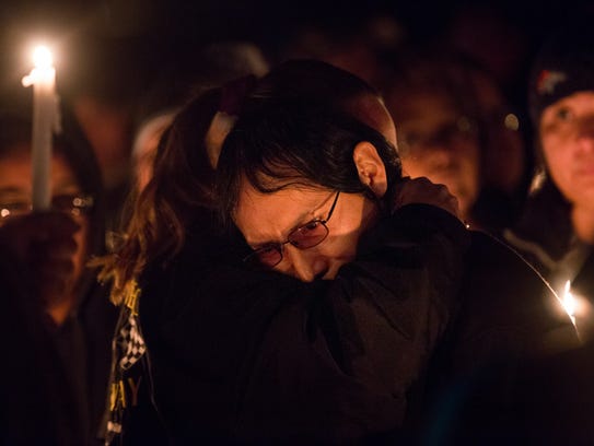 Lemuel Sam is comforted during a candlelight vigil on Friday in Kirtland.