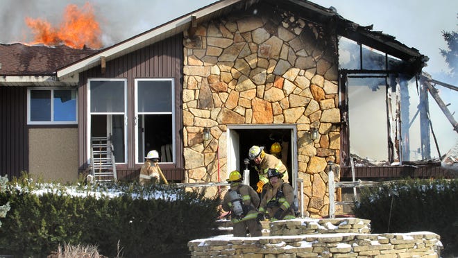 Firefighters work at the front of a home of Brent Drive in Marion Township on Thursday. Two people died in the blaze.