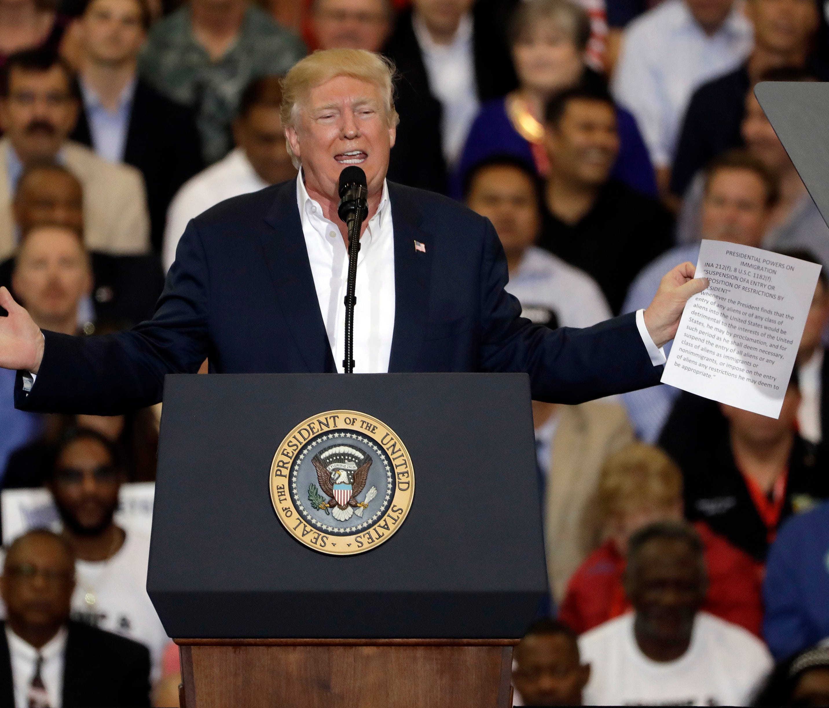 President Trump gestures as he holds up a piece of paper on the presidential powers on immigration during a campaign rally on Feb. 18, 2017, at Orlando-Melbourne International Airport.