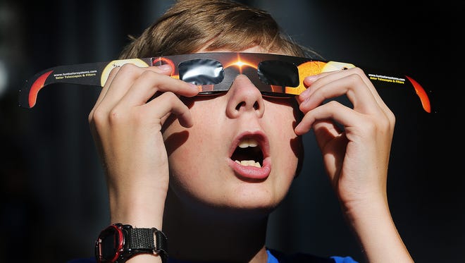 FILE - In this Wednesday, Aug. 16, 2017 photo, Colton Hammer tries out his new eclipse glasses he just bought from the Clark Planetarium in Salt Lake City in preparation for the Aug. 21 eclipse. Eye doctors urge strict adult supervision for eclipse watchers under 16 years old.
 (Scott G Winterton/The Deseret News via AP)