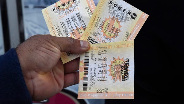 A man holds out his Powerball lottery tickets and...