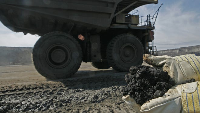 A mine worker holds a handful of tar sands oil in 2006 at a mine located 35 miles north of Fort McMurray, Alberta. It takes about two tons of this stuff to produce one barrel of oil.