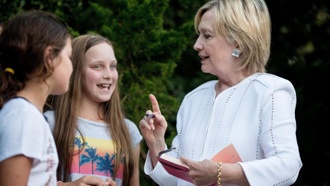 Democratic presidential candidate Hillary Clinton speaks with neighborhood children as she signs a book for them following a fundraiser at a private home in Sagaponack, N.Y., Tuesday, Aug. 30, 2016.