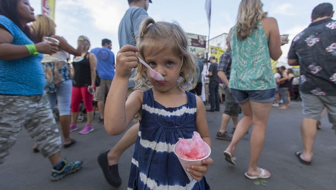 Mila Bader, 3, eats a spoonful of her snow cone during the 2016 Taste of Fort Collins.
