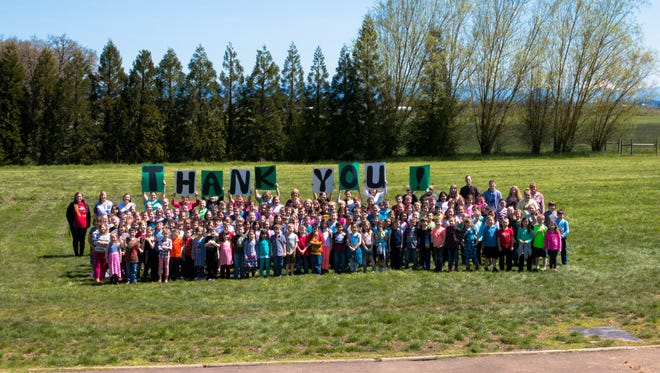 Cloverdale Elementary School students gather in a recreational field, a former patch of weeds and marshland that was groomed by community members, businesses and donations so it could be used playing games. Each person who donated time and equipment will be presented with a framed copy of the photo during a brief assembly at the school on Monday, June 12.
